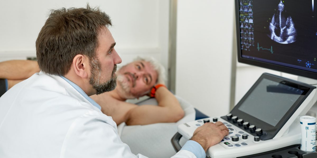 Arzt führt Herzultraschall bei Patient durch, während Ergebnisse auf dem Monitor angezeigt werden.