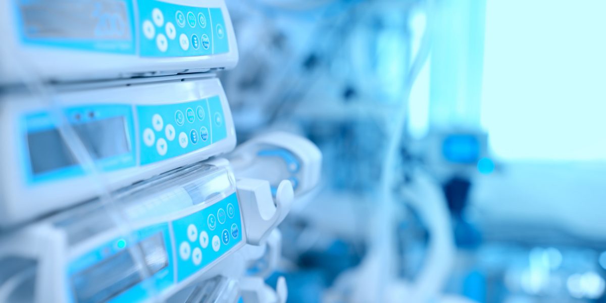 Klinische Infusionspumpen in einem Krankenhaus mit hellem Blaustich. Naheaufnahme von Geräten mit Tastenbedienfeld.