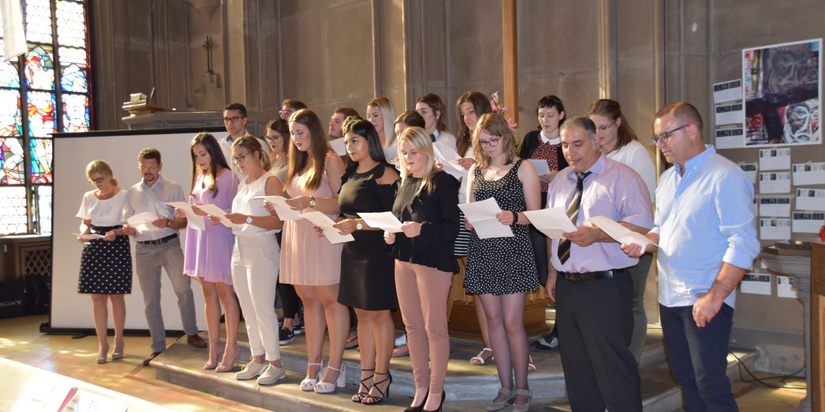Gruppe von Menschen steht in einer Kirche und singt gemeinsam aus Notenblättern.