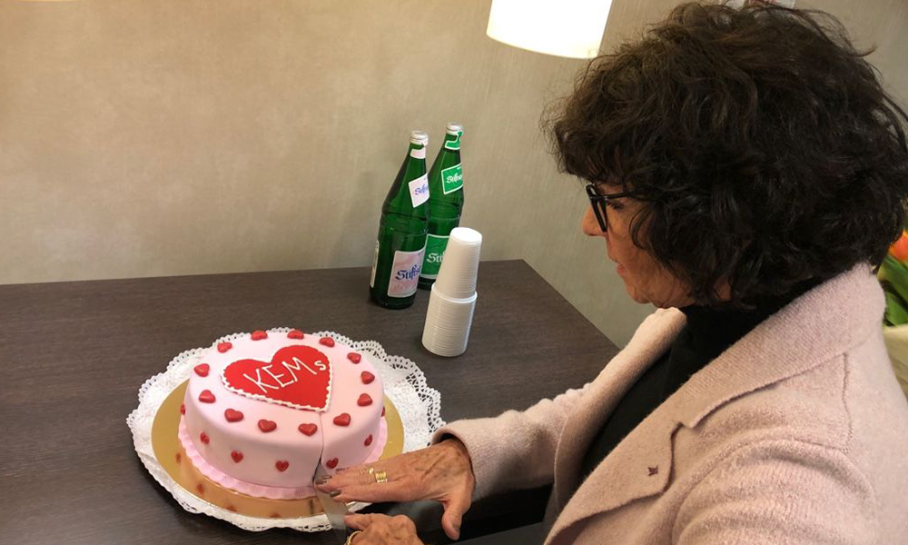 Frau schneidet eine rosa Torte mit kleinem Herzen und der Aufschrift