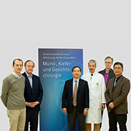 Sechs Männer stehen vor einem Banner mit der Aufschrift 