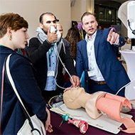 Menschen schauen sich ein medizinisches Simulationsmodell an; einer zeigt darauf und erklärt.