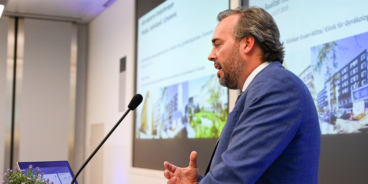 Ein Mann hält eine Präsentation in einem modernen Konferenzraum vor einer Leinwand mit Projektionsfolie.