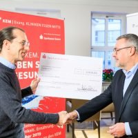 Zwei Männer bei der Übergabe eines symbolischen 4.000-Euro-Schecks der Sparkasse Essen an die Kliniken Essen-Mitte.
