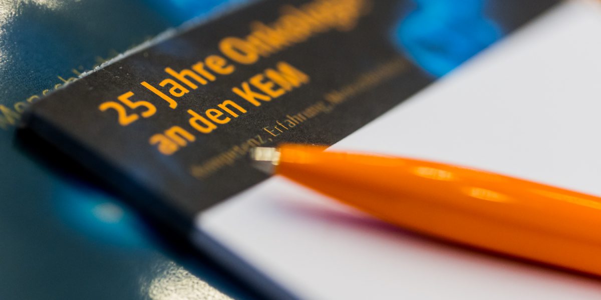 Orangefarbener Kugelschreiber auf einem Flyer mit der Aufschrift 