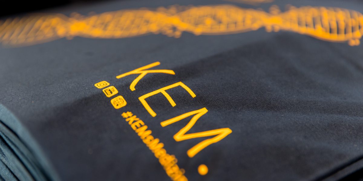 Nahaufnahme eines schwarzen Stoffes mit gelbem DNA-Muster, dem Schriftzug 