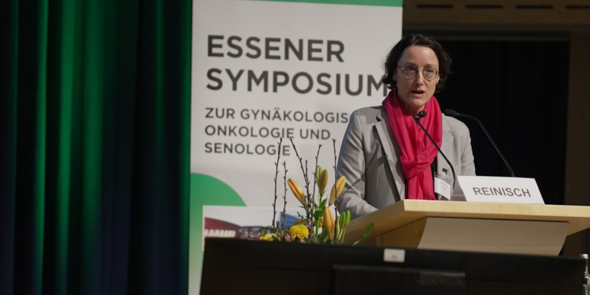 Frau spricht beim Essener Symposium zur Gynäkologie; steht an einem Pult mit Namensschild und Mikrofon.