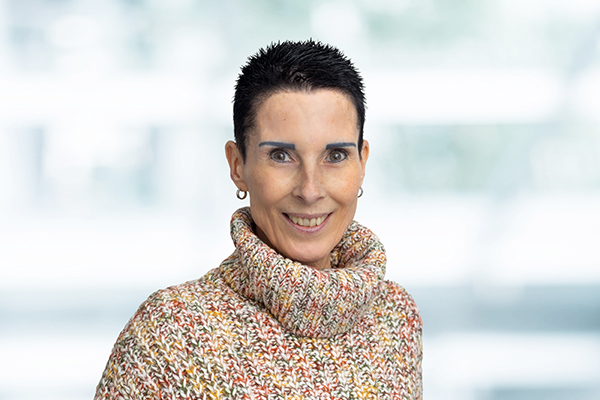 Es tut mir leid, ich weiß nicht, wer auf dem Bild ist. Eine Person mit kurzem dunklem Haar trägt einen bunten Rollkragenpullover.