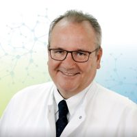 Porträt eines lächelnden Mannes in weißem Kittel und Brille, vor einem wissenschaftlichen Hintergrund.