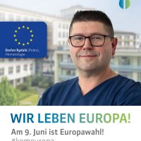 Porträt eines Mannes mit Brille vor einem Gebäude. Text: 