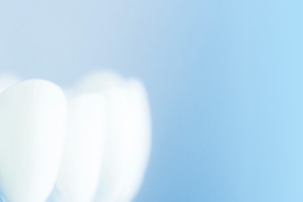 Nahaufnahme von weißen, glänzenden Zähnen auf blauem Hintergrund.