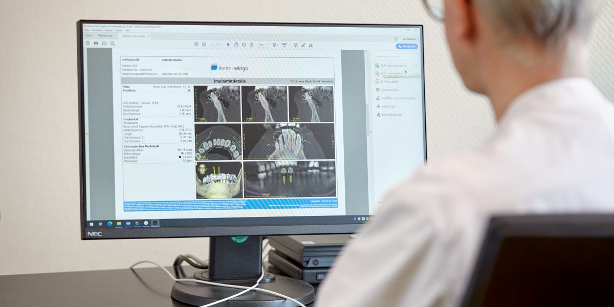 Person analysiert Zahnimagery auf einem Computerbildschirm in einem medizinischen Büro.